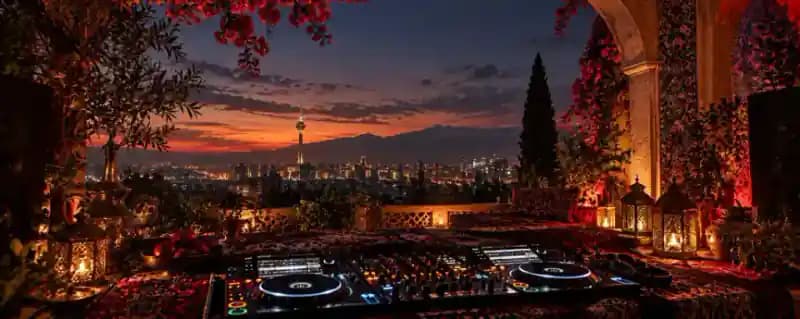DJ decks on a terrace at dusk, looking out over a city skyline
